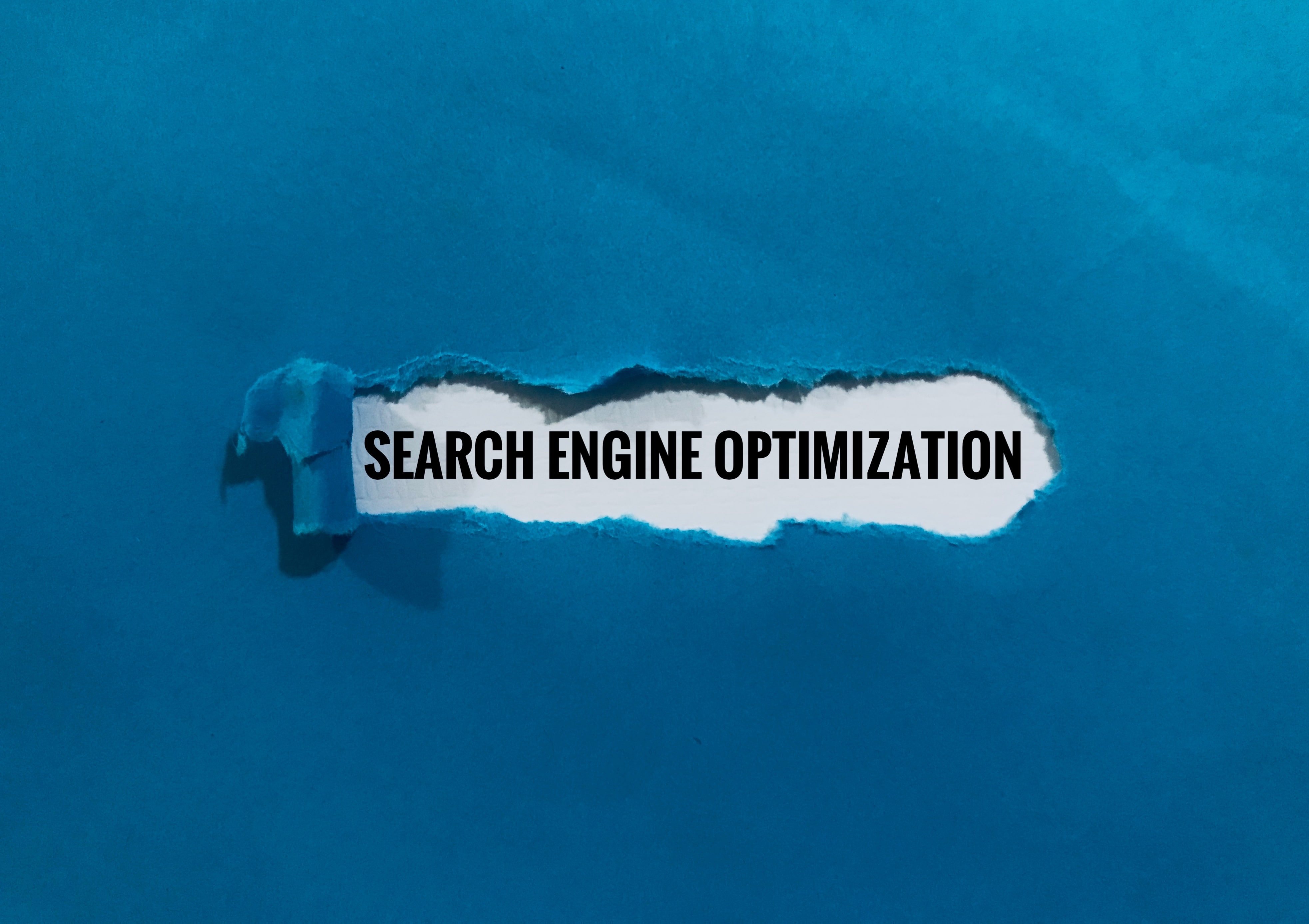 Blue torn paper revealing the words 'Search Engine Optimization' in bold black text, symbolizing uncovering digital strategies for online visibility and SEO growth.