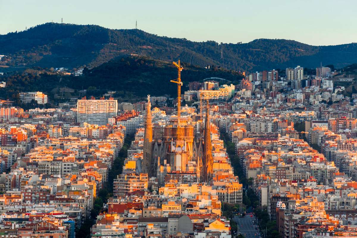 Aerial view of Athens at dusk with the illuminated Parthenon and Acropolis overlooking a dense city and hills.