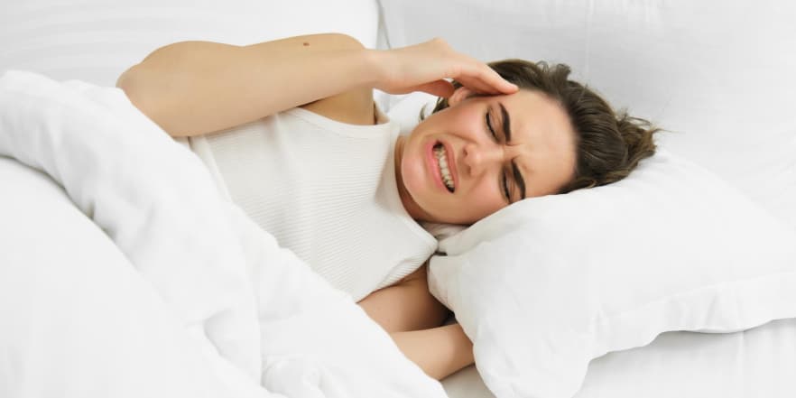 Жінка скреготить зубами, лежачи у ліжку