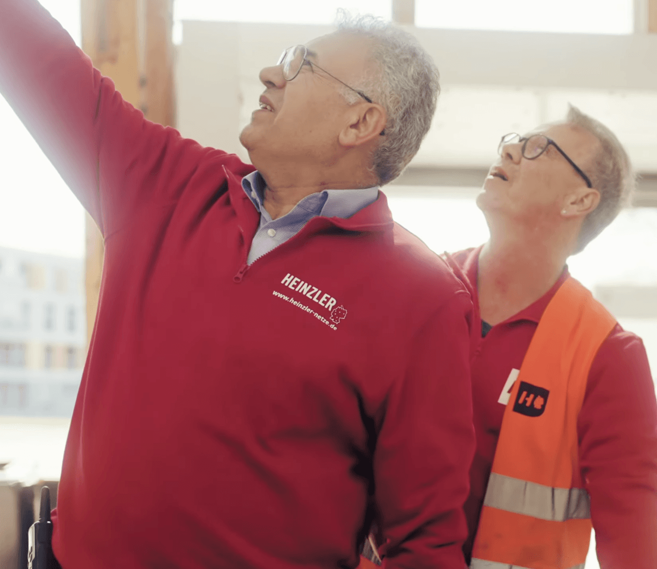 Mature man with glasses and a trimmed beard smiling confidently, standing in warm natural light against a modern backdrop.