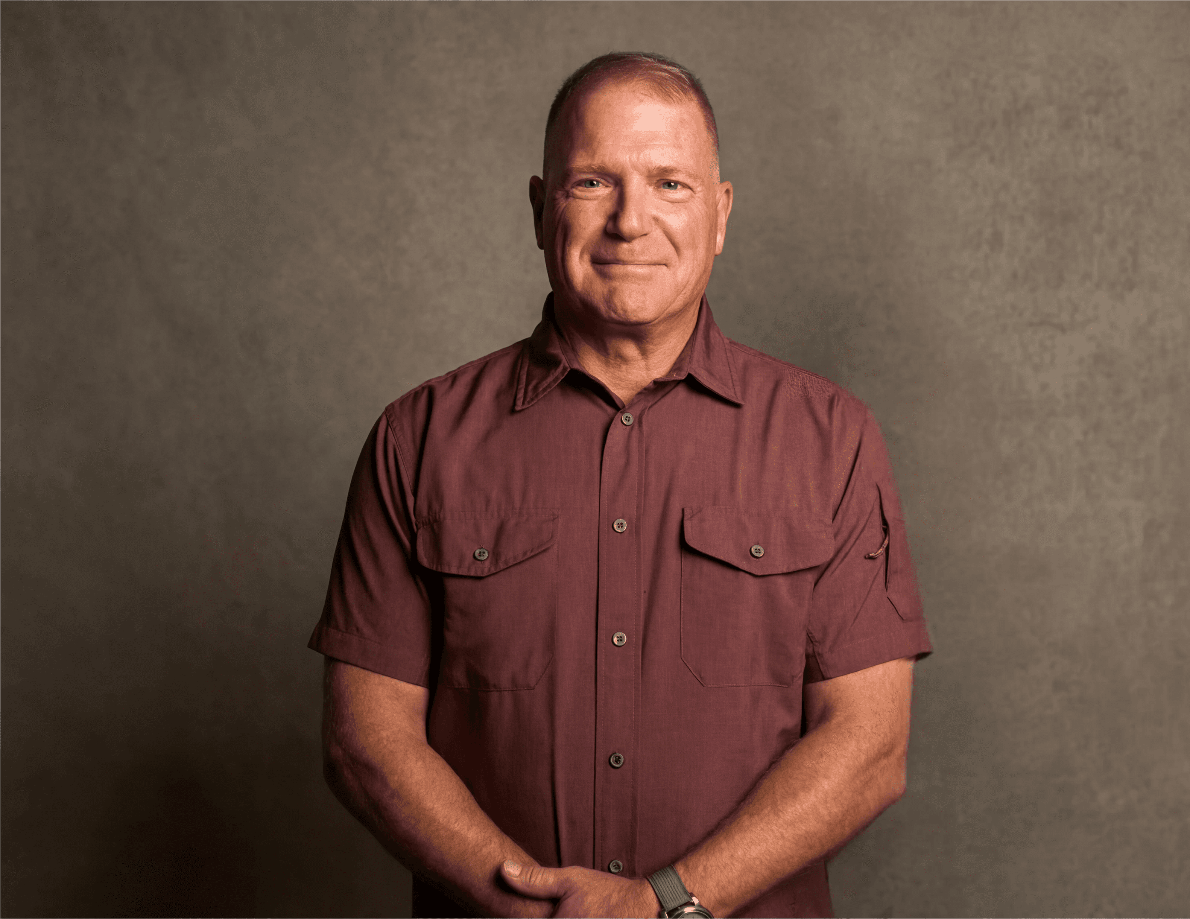 Man with curly hair wearing brown hat and dark shirt.