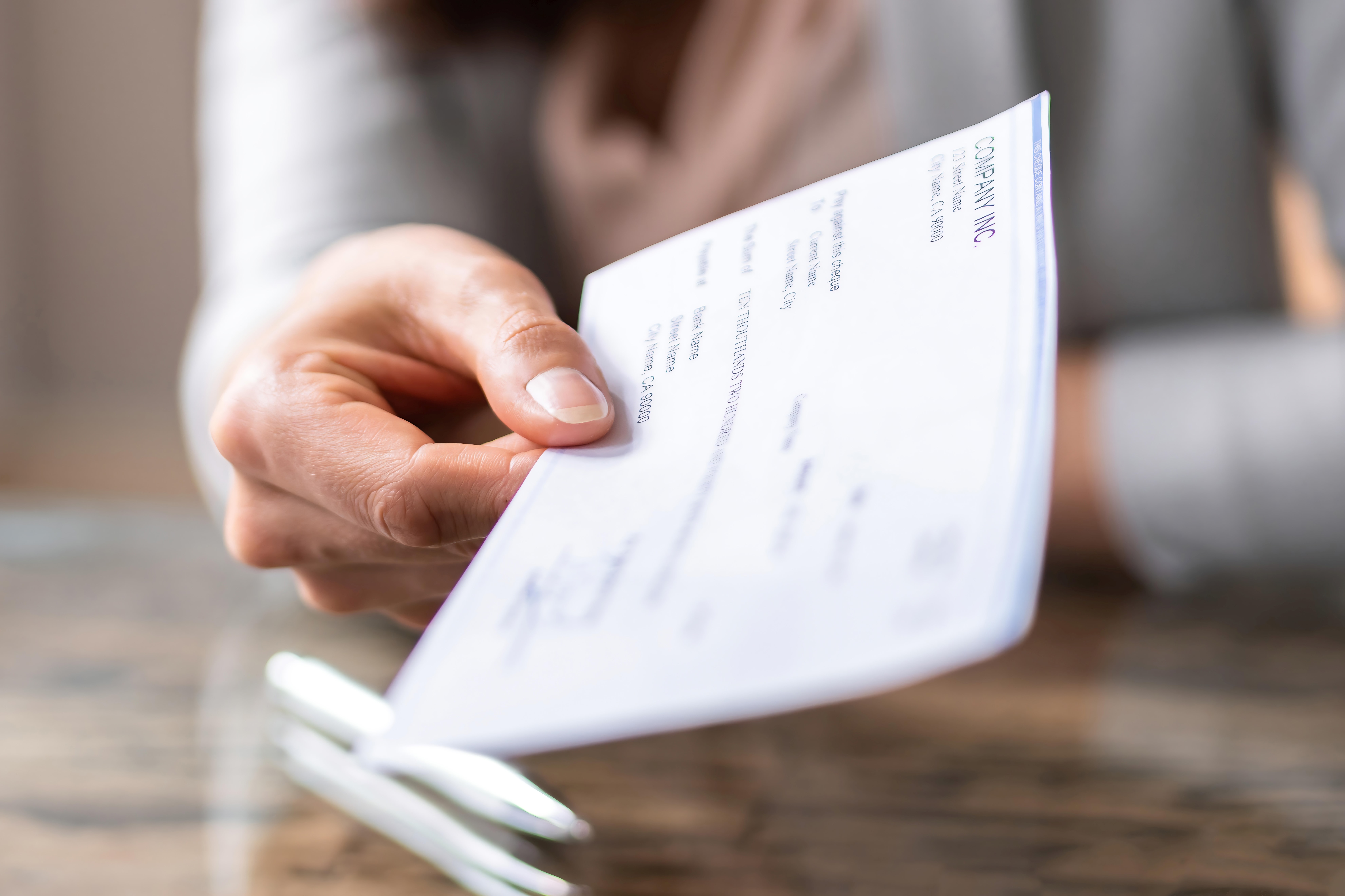Close-up of a person holding a cheque on a table