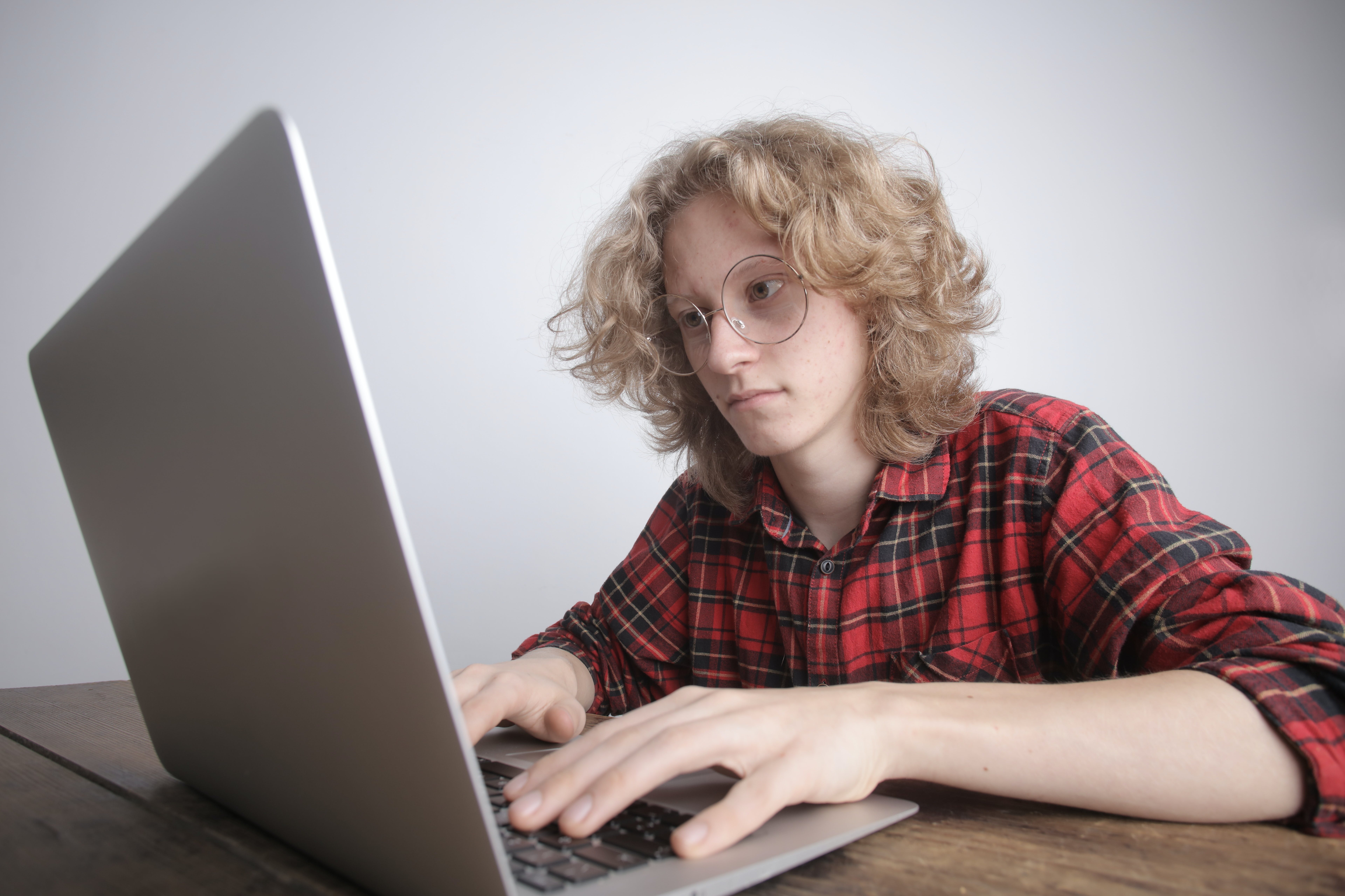 Woman in red and black shirt using macbook to follow up cold emails