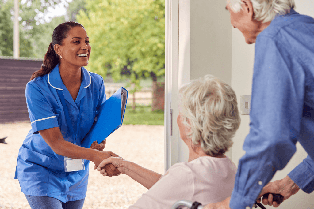 Senior Couple With Woman In Wheelchair Greeting Nurse