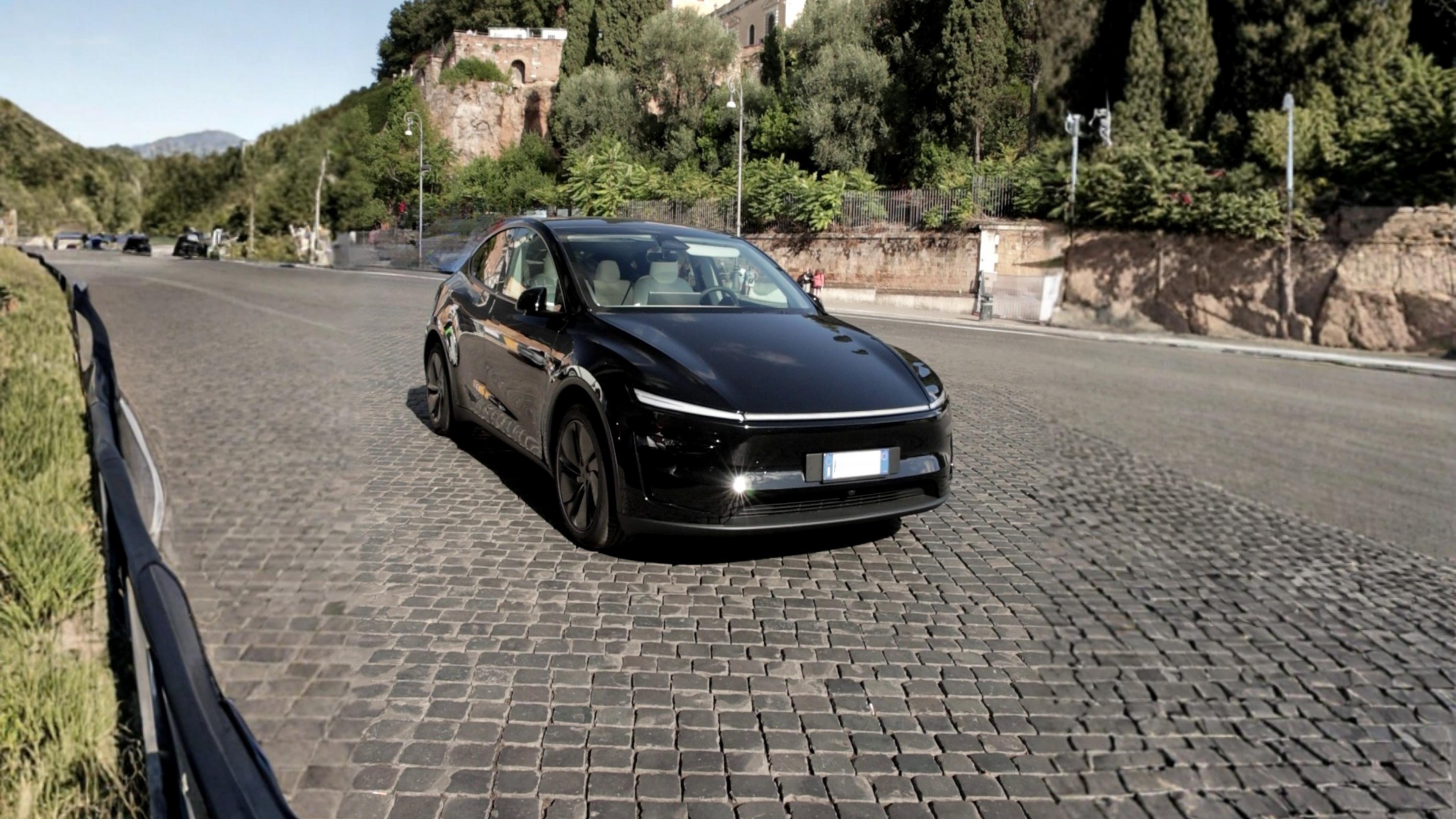 A picture of a Tesla Model Y along a brink road in the middle of a park in Italy.