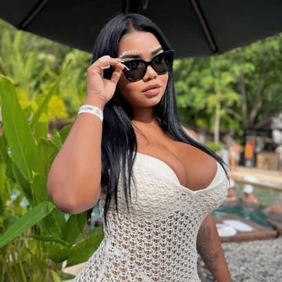 Mujer con vestido negro ajustado y escote pronunciado, posando en un ambiente iluminado con luz púrpura.