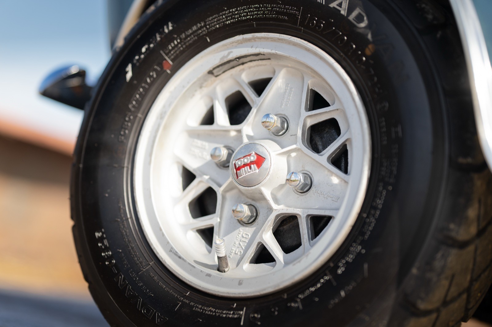 Close-up of a vehicle wheel with a silver rim and black tire, showcasing intricate design details.