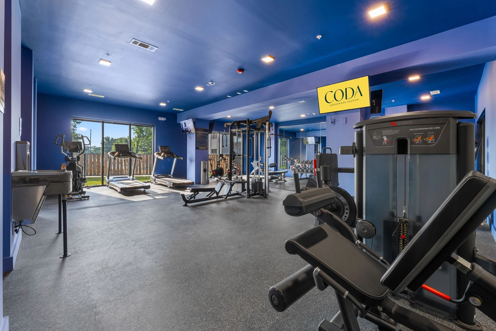 A gym room featuring blue walls and various fitness equipment arranged for workouts.