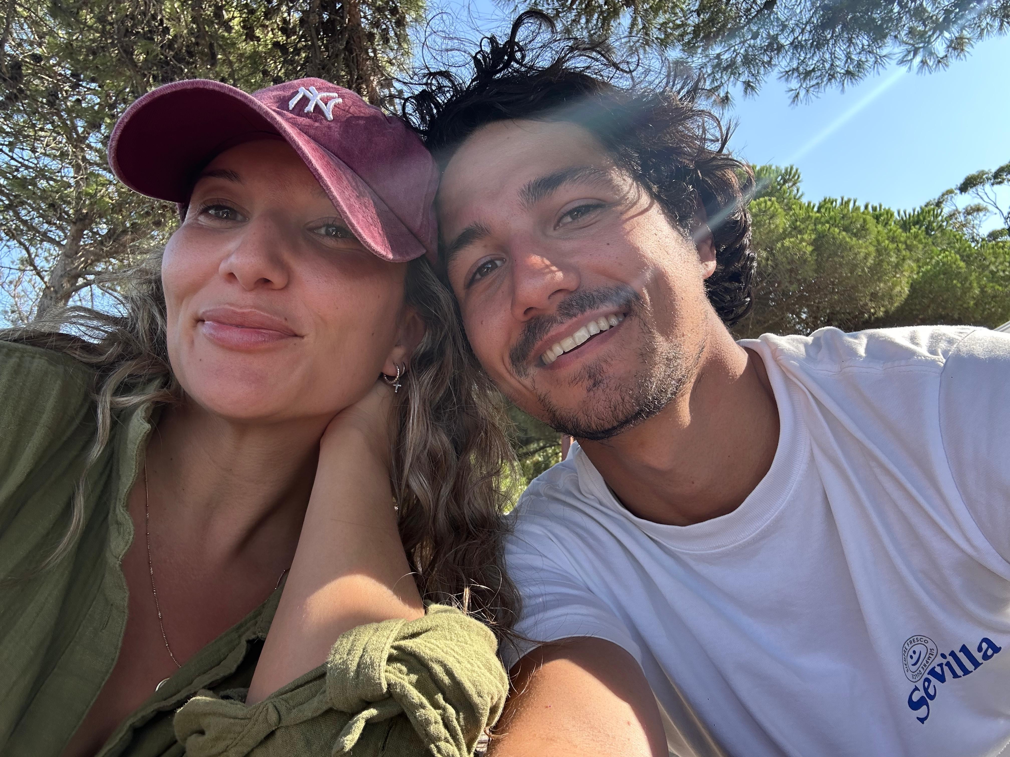 A young person with long, wavy hair sits in front of a plain background, looking directly at the camera.
