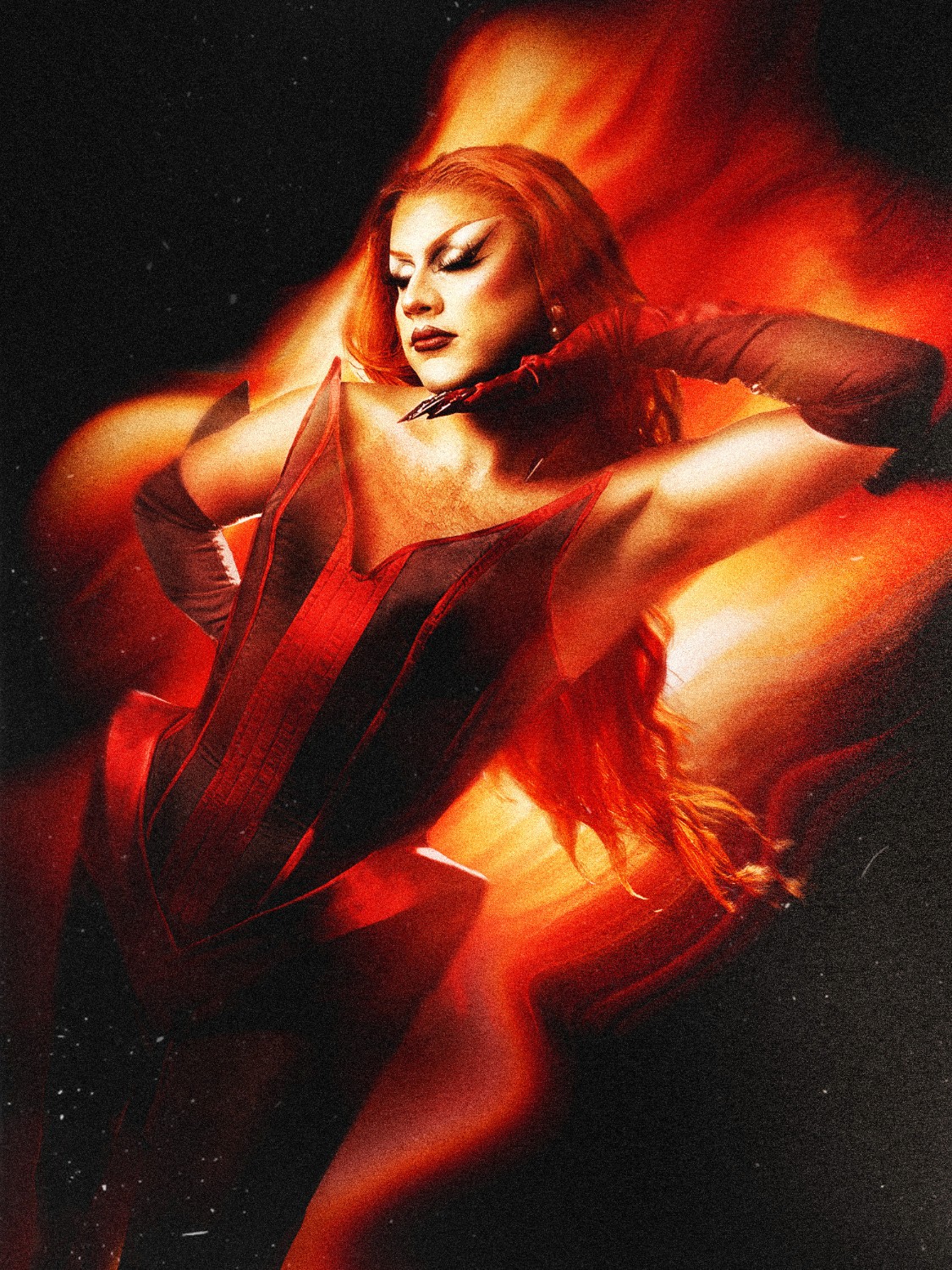 A captivating fine-art photograph by DramatK (Lélio Bazin), showcasing a person in a deep red corset and long red hair posed against a dramatic, abstract background of bright orange and red flames with dark smoke.