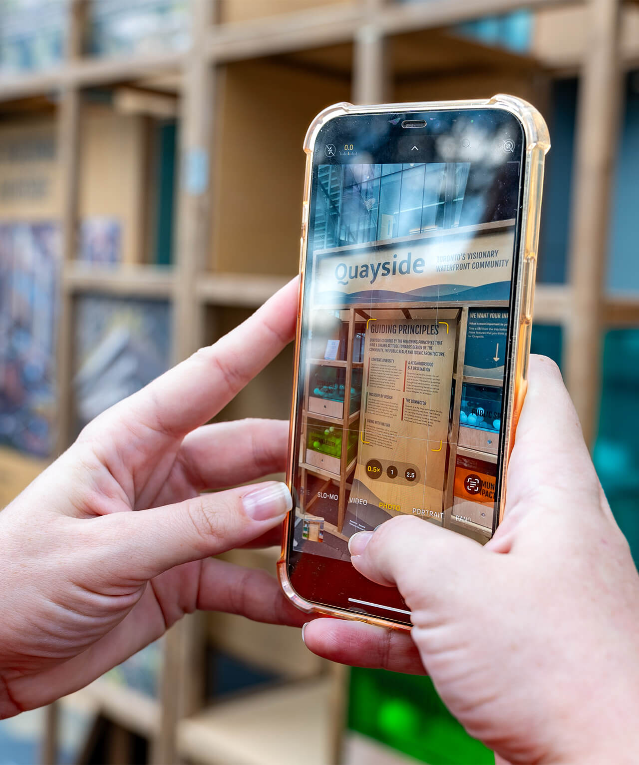 Closeup of a person taking an iPhone photo of the Quayside exhibit.