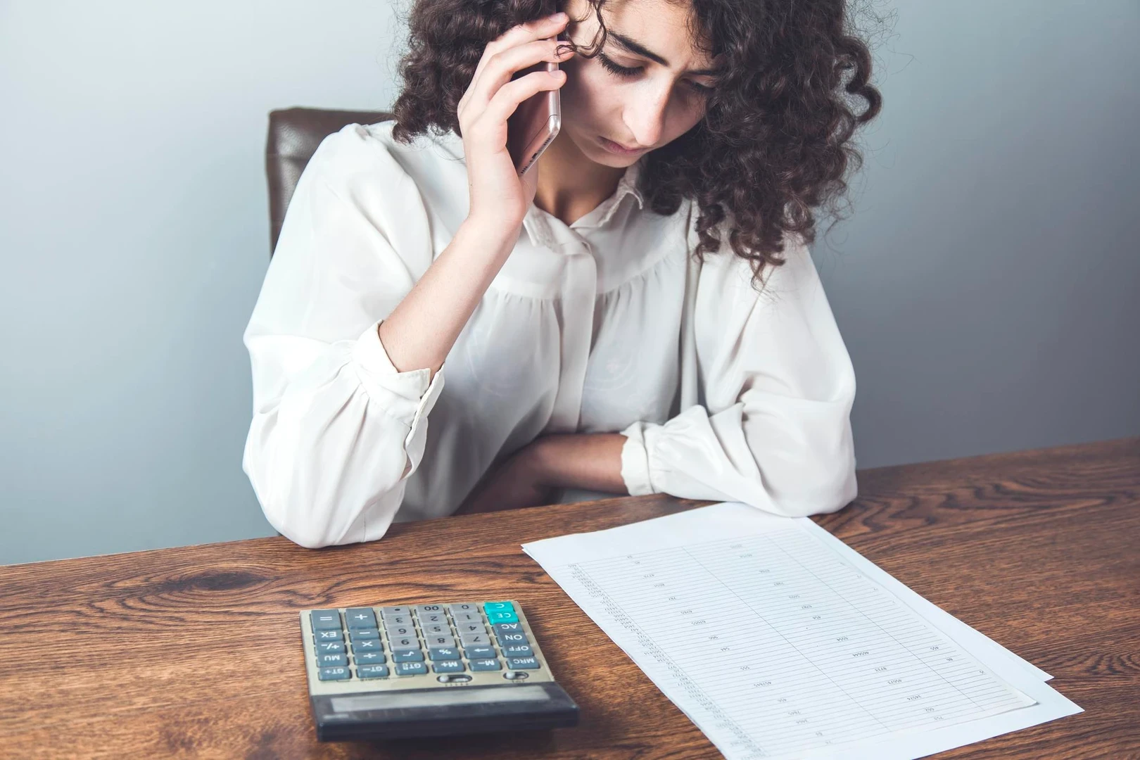 Woman talking in smart phone with hand documents
