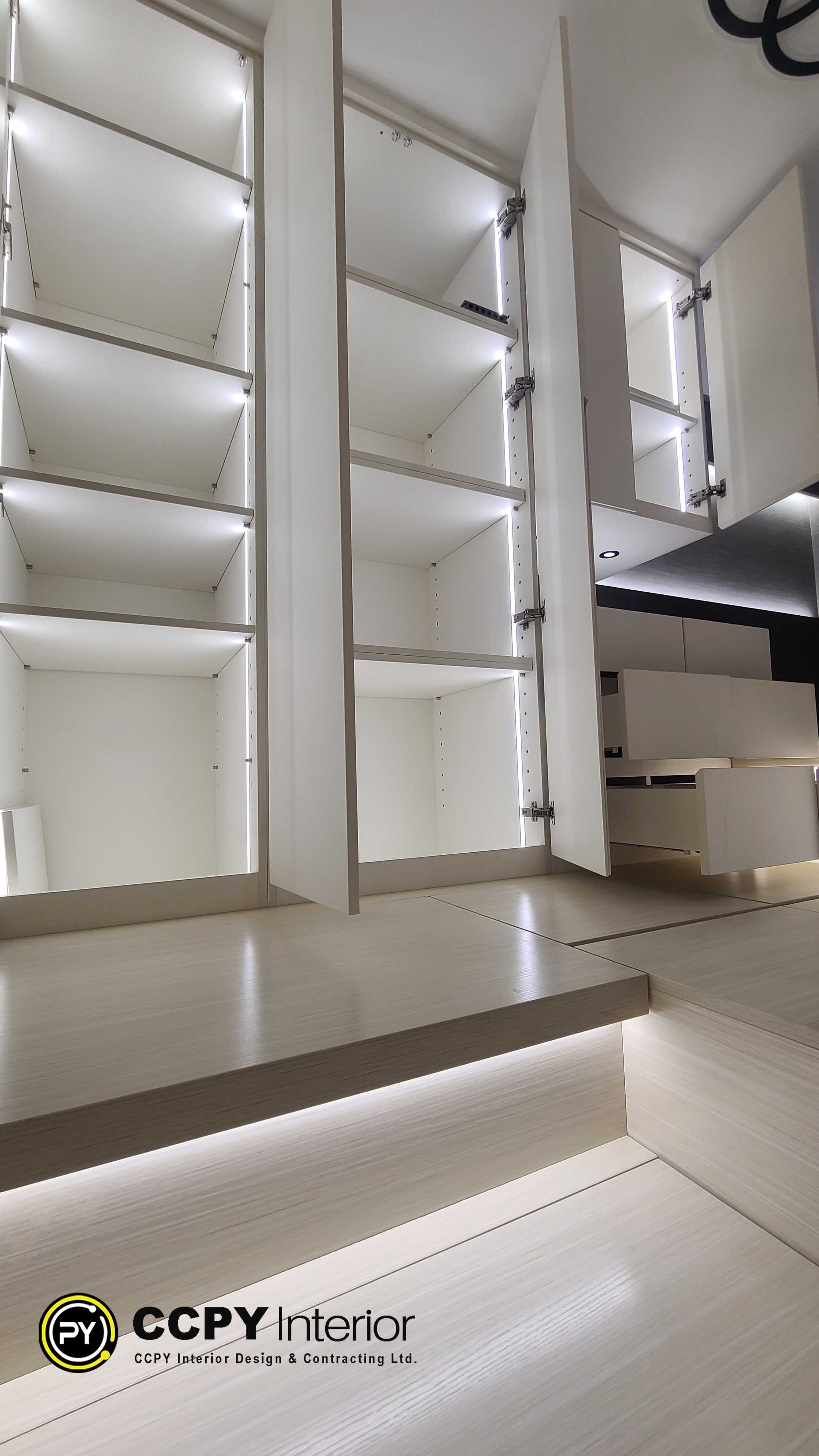 The selected region shows a modern, custom-built wardrobe or cabinetry unit featuring integrated vertical LED strip lighting along the interior side panels. The cabinet doors are open, revealing clean white or light gray shelves, open compartments, and high-quality metal hinges.Key Design and Structural FeaturesIntegrated Lighting: Recessed vertical LED strips illuminate the entire interior, making items easy to find while adding a luxury feel.Cabinet Construction: The unit uses thick, solid vertical dividers and adjustable shelving pins to allow custom height configurations.Hardware: Heavy-duty, concealed European-style hinges are used for smooth door operation.Flooring Integration: The cabinetry is built flush against the floor tiles, creating a seamless, built-in architectural look.