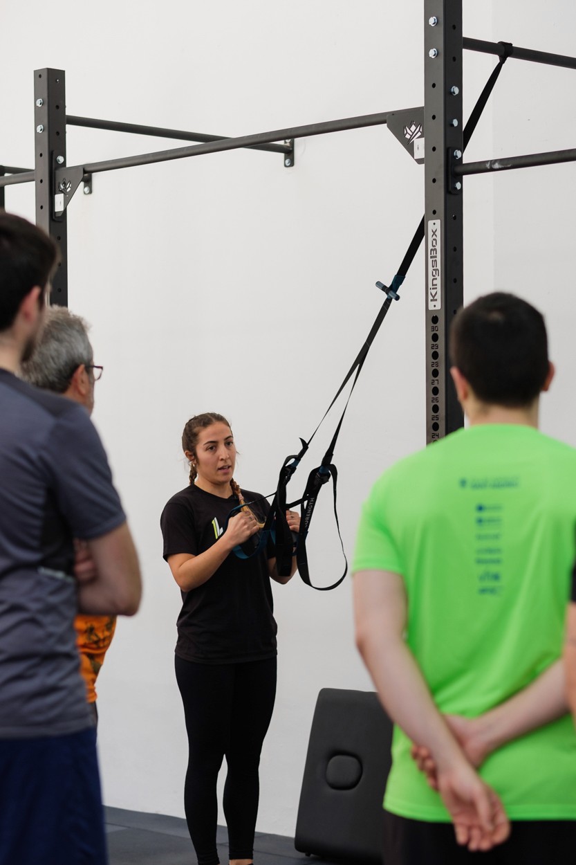 Entrenadora explicant com es fa servir la TRX per l'exercici de força al gimnàs de One Life a Gracia, Barcelona.