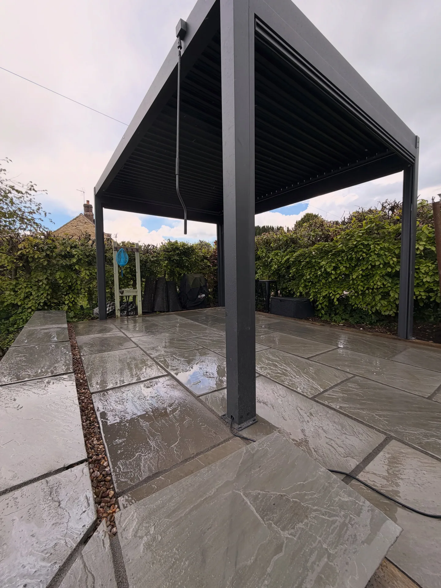 Black pergola installed over a finished Indian stone patio in York