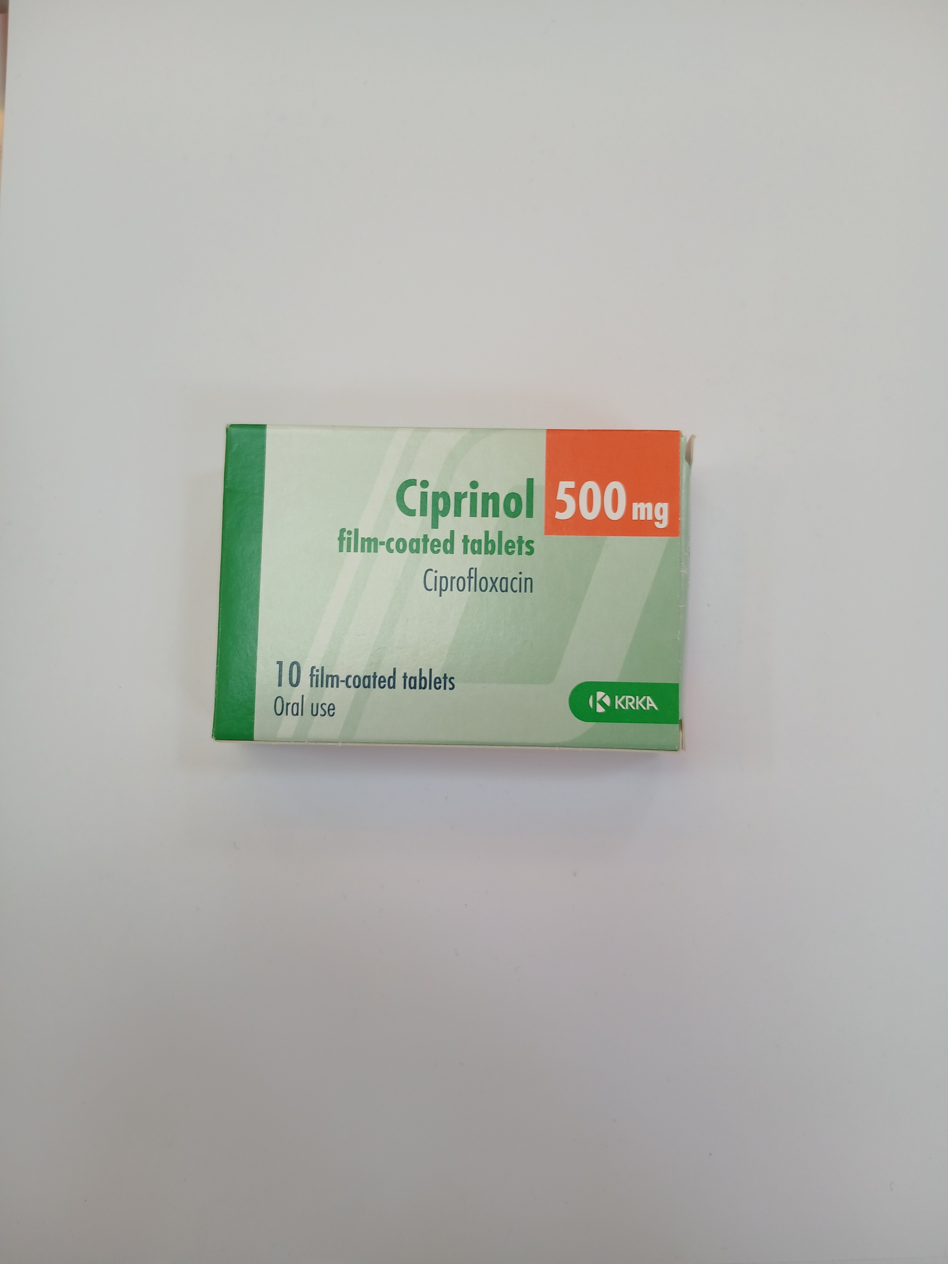 A white and green cardboard box packaging contains ten film-coated tablets arranged inside, with printed text indicating dosage and usage instructions.