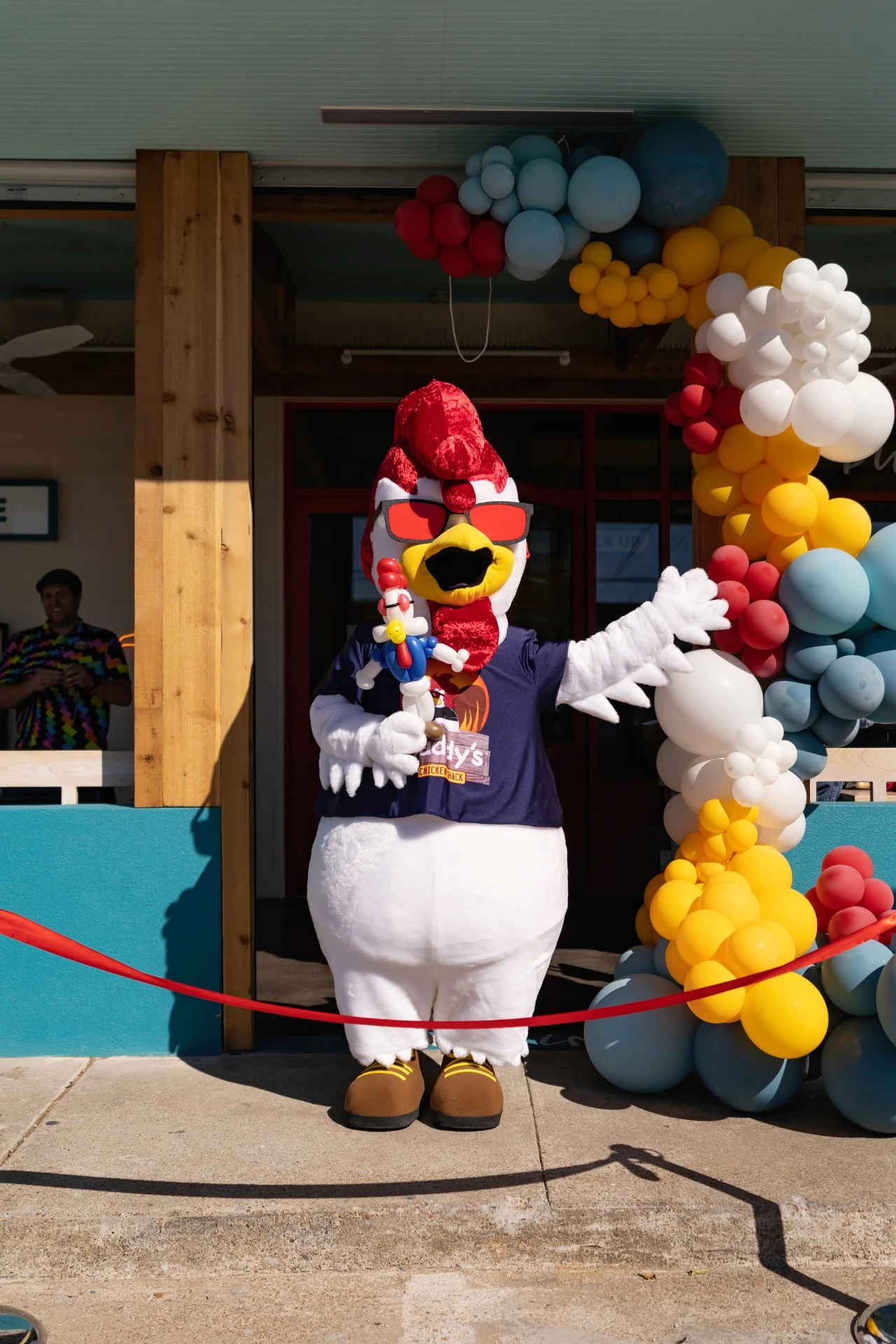 Daddy’s Chicken Shack mascot beside grand-opening balloons