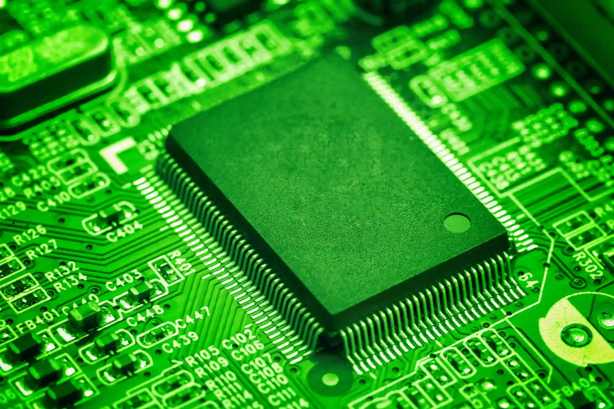 A close-up of a green electronic circuit board with a central processor chip, highlighting core hardware and technology.