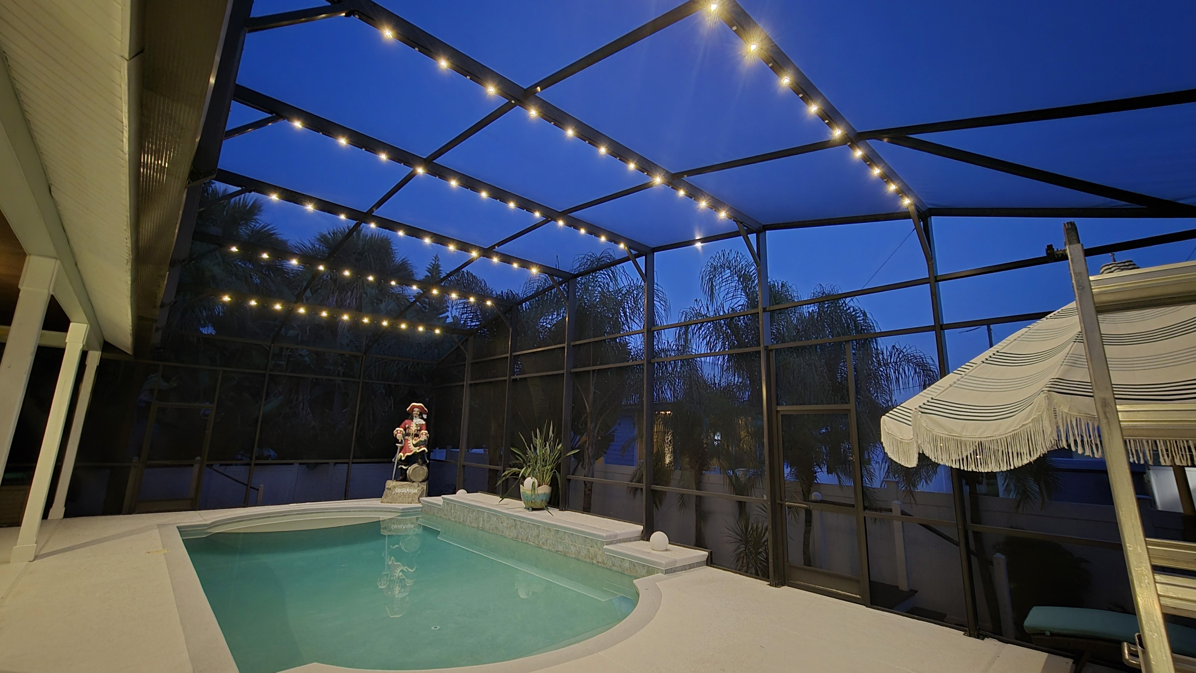 Screened pool enclosure with warm bistro-style overhead lighting
