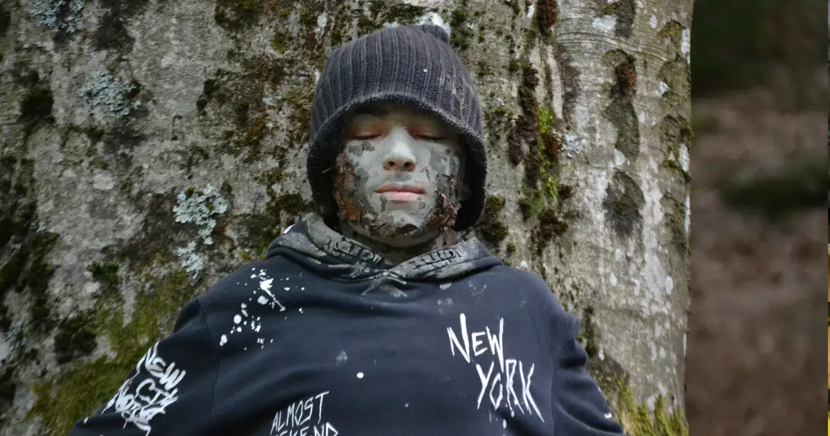 bambino mimetizzato con tecniche di sopravvivenza bushcraft e indigeno primitive nella foresta