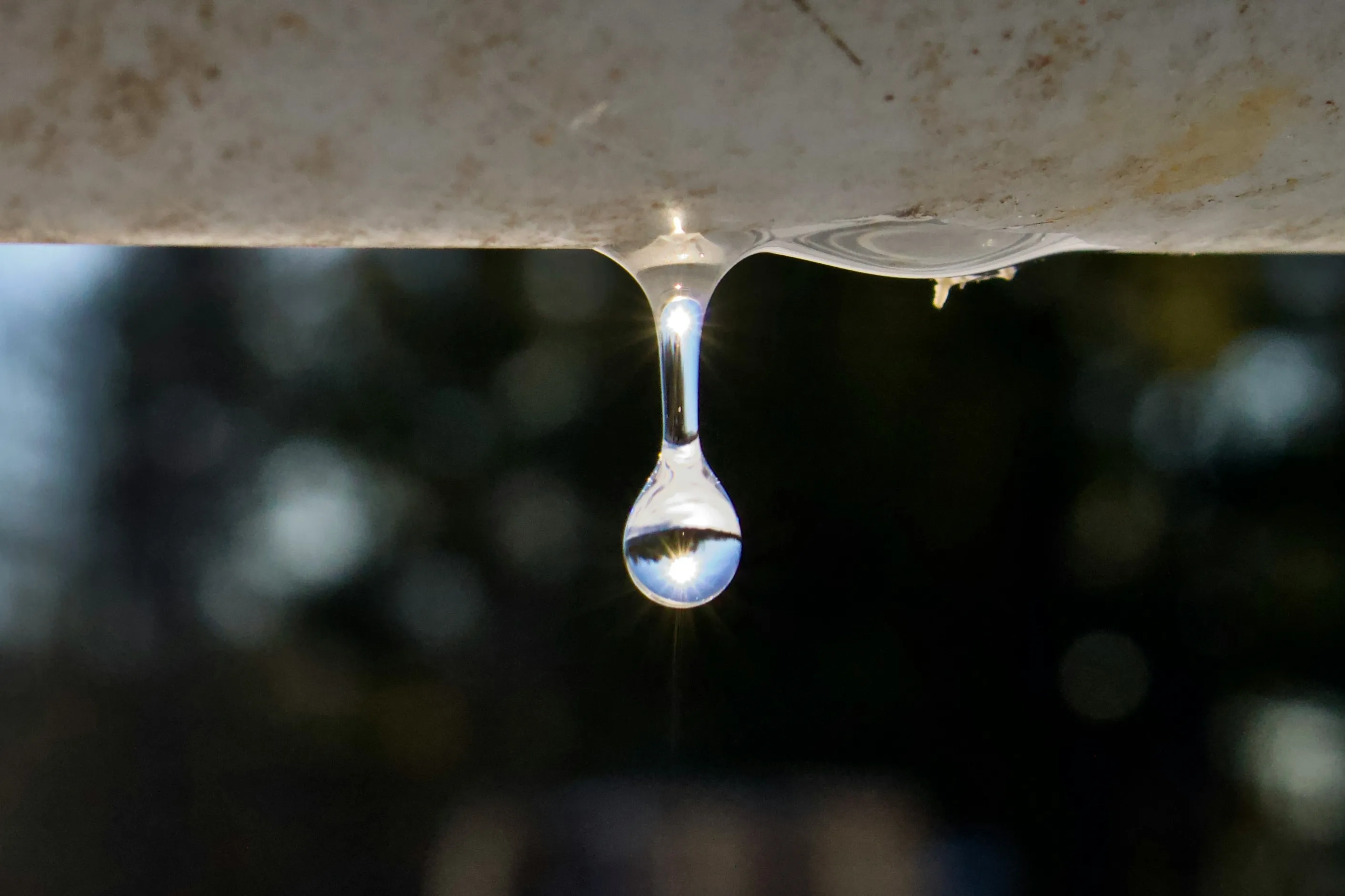 A single water drop hanging from a pipe