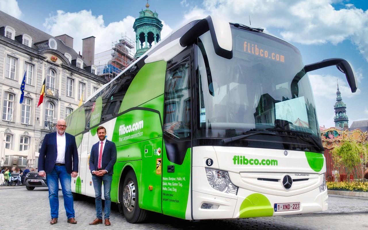 Busfahrer posiert mit grün-weißem Tourbus in London.