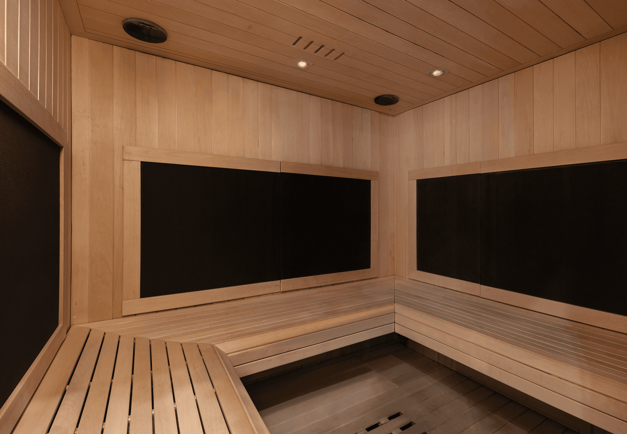 A wooden sauna interior featuring bench seating and dark walls, creating a warm and inviting atmosphere.