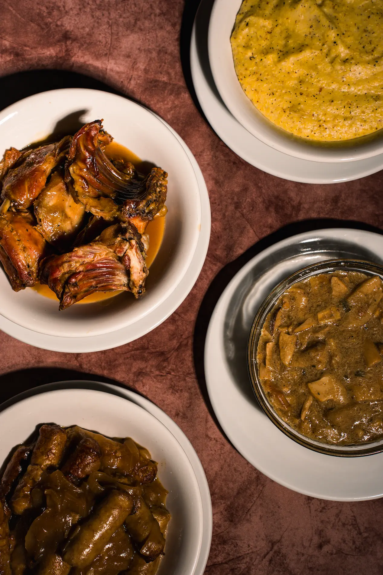 A group of smiling people, dressed in casual light-colored clothing, walks joyfully through a charming cobblestone street lined with market stalls, each person carrying baskets overflowing with fresh produce, bread, and flowers.