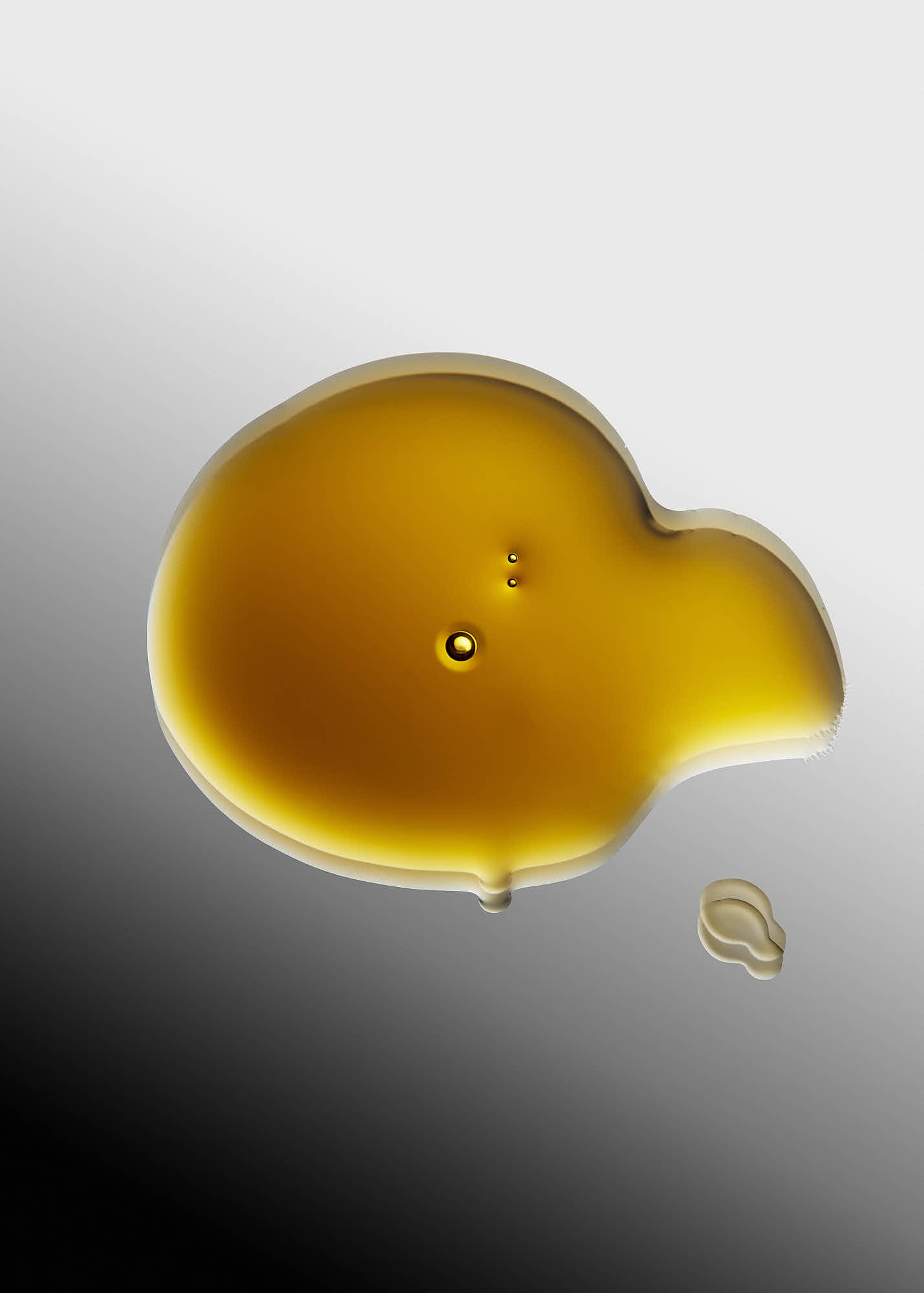 A small, glossy, amber-colored blob on a smooth, dark background.