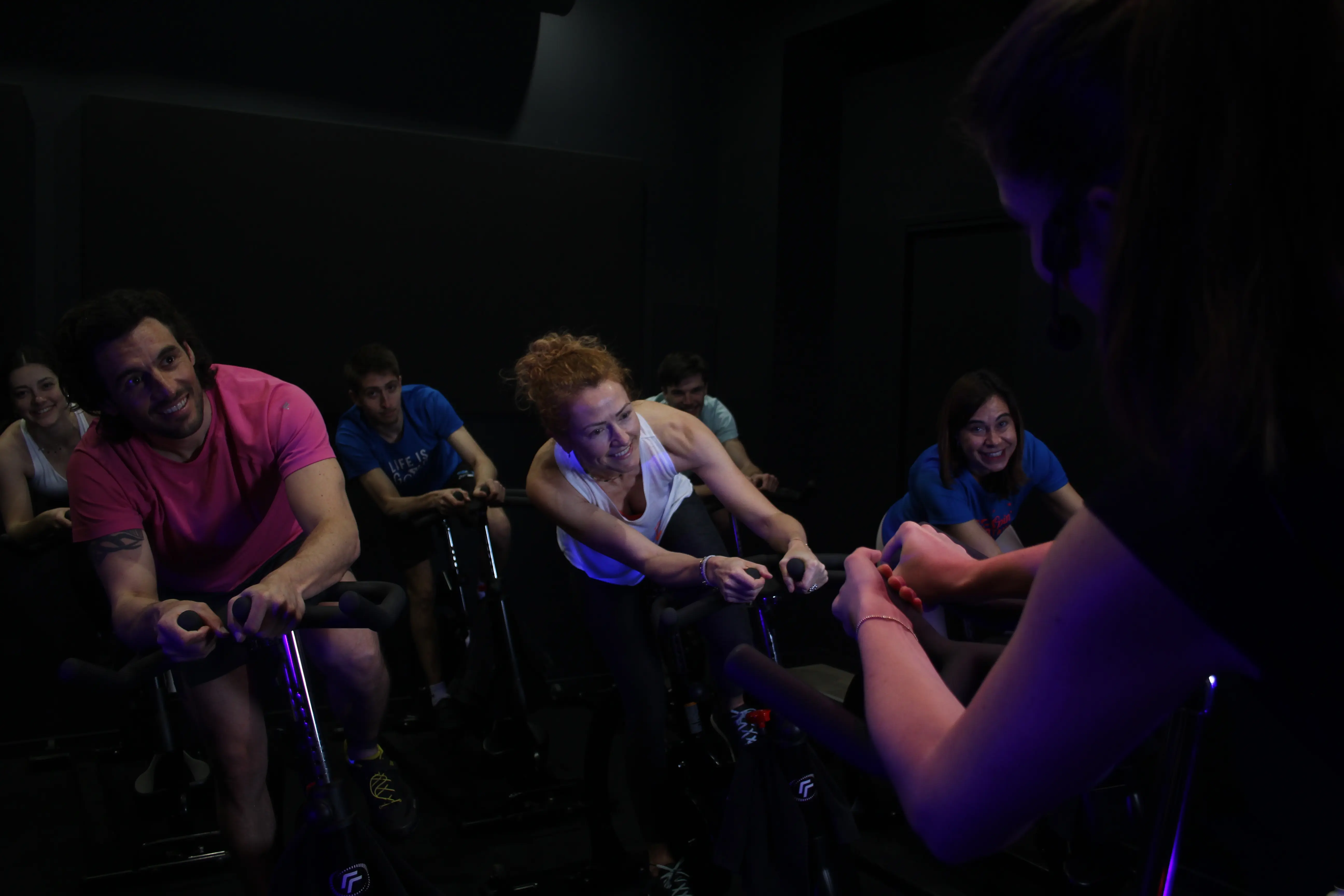 Groupe de participants en séance de cycling encadré par une coach dans la spin room sombre de Spinbreak Bordeaux