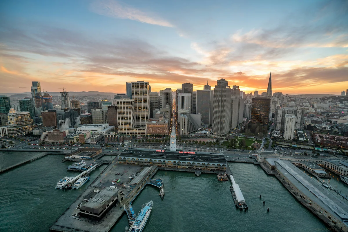 Aerial view of downtown San Francisco skyline and Embarcadero waterfront at sunset.