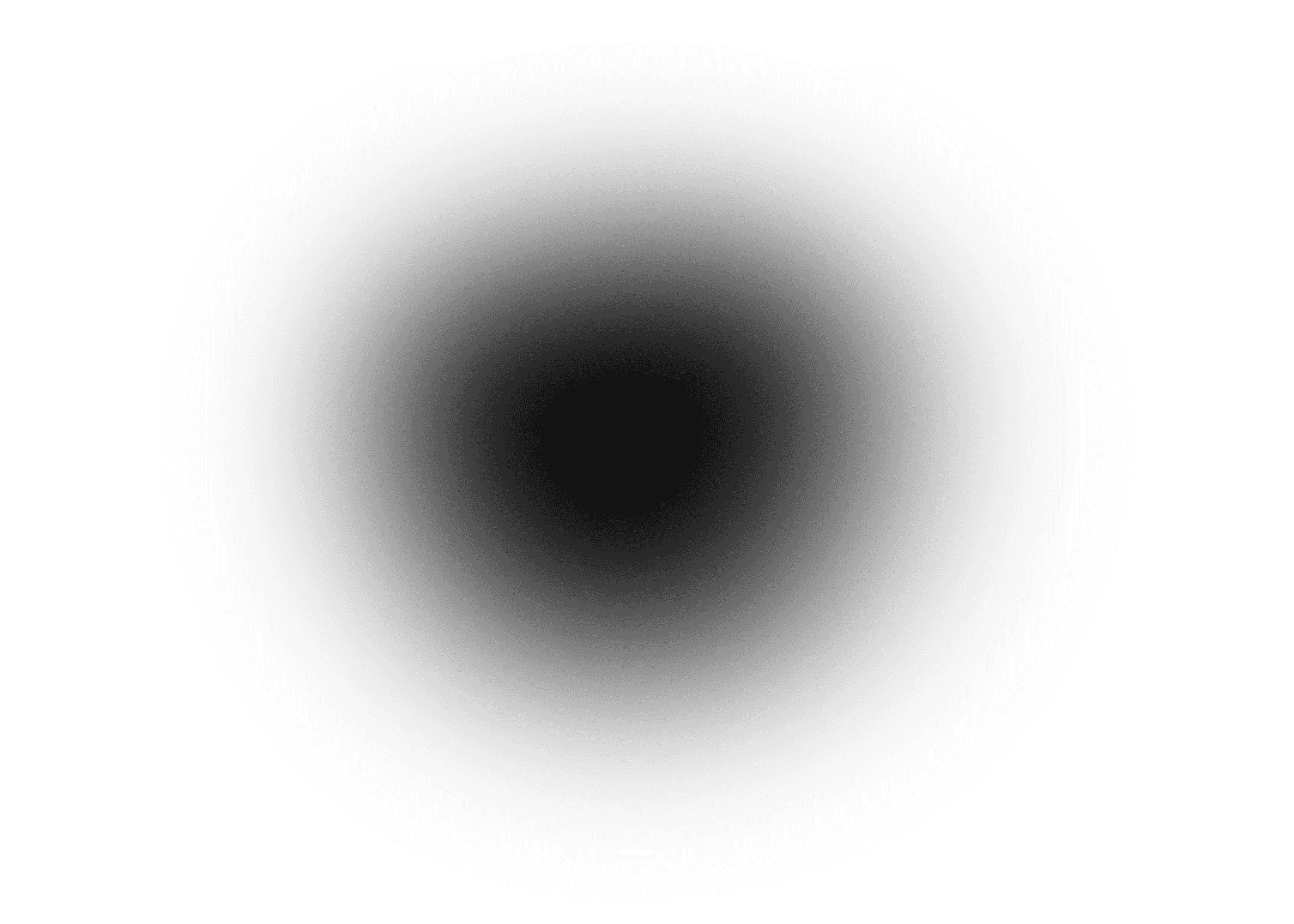 A smiling person with curly hair sits at a desk, looking at a laptop against a dark background.