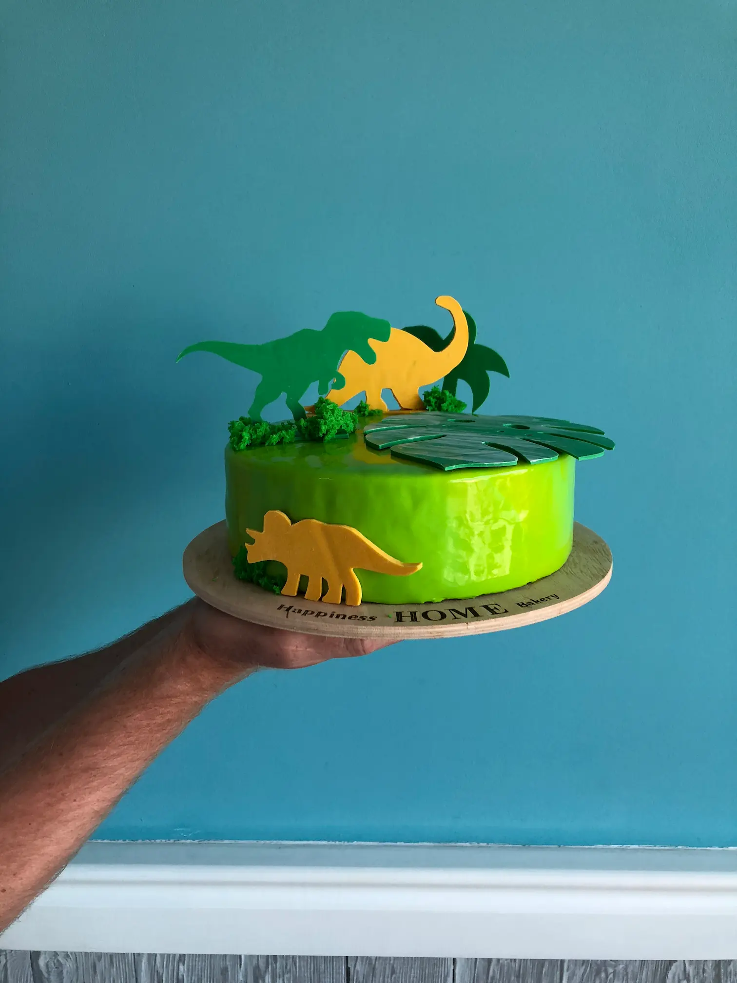 Vibrant green coconut cake with yellow mango layer and dinosaur figurines on top