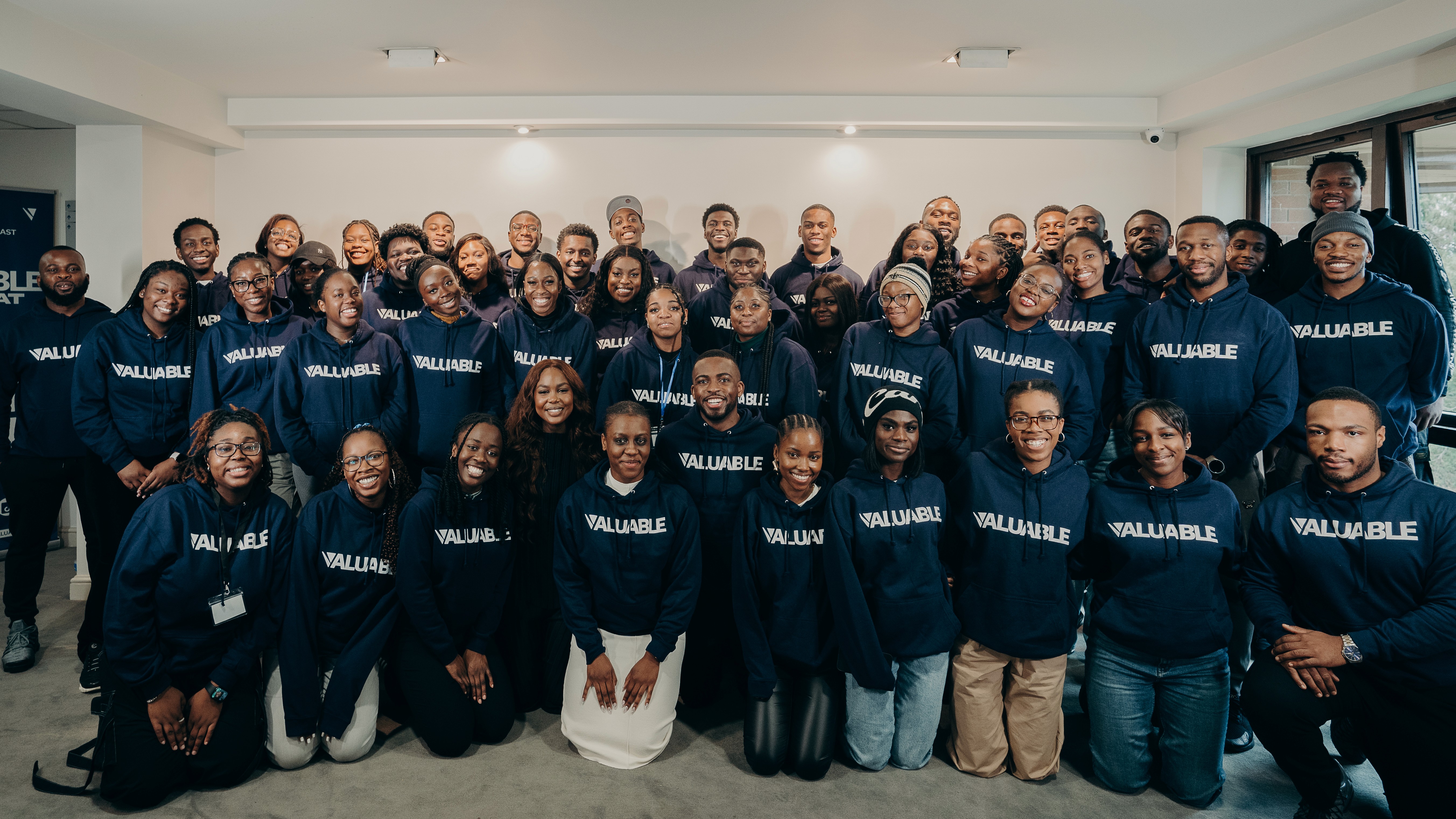 Large group of people from the Valuable community wearing navy sweatshirts, posing for a photo indoors.