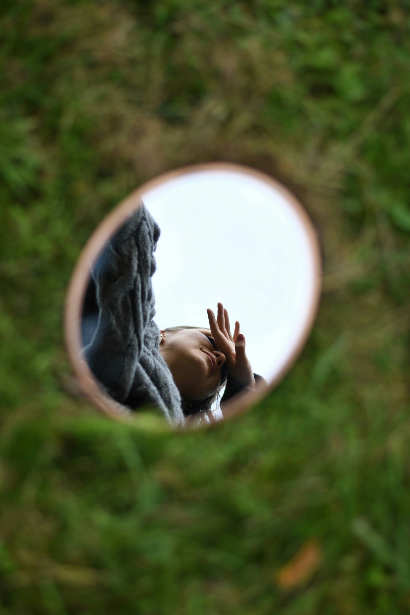 A cozy and inviting spa room with a neatly made bed, soft lighting, and warm wooden tones. The scene is partially framed by green plants, adding a natural and soothing touch.
