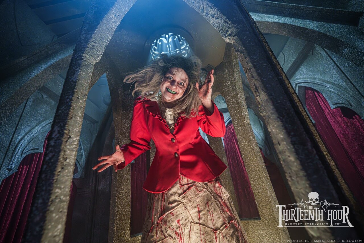 Screaming scare actor in a red jacket reaching toward the camera