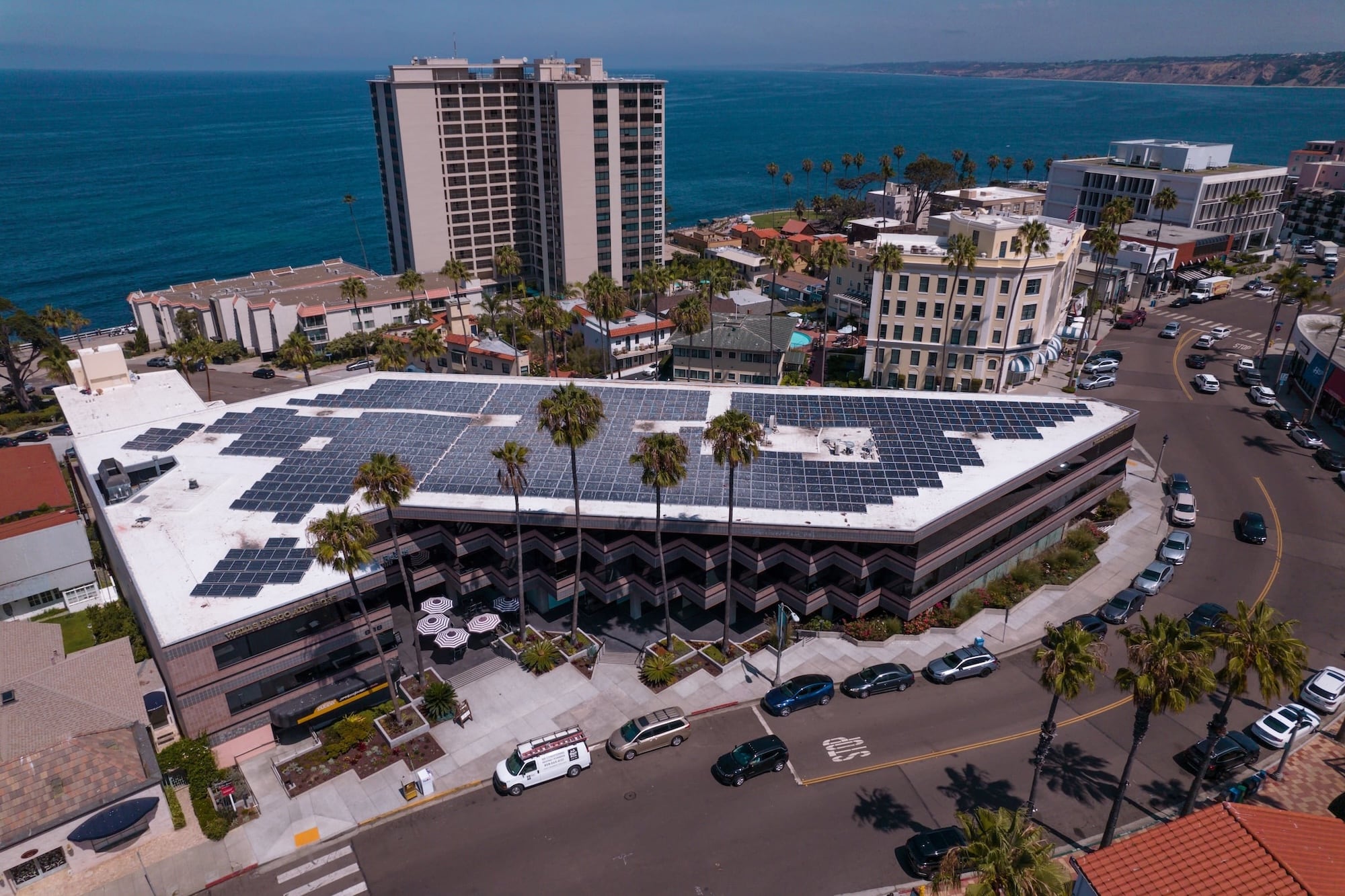 Aerial view of a coastal office building whose flat roof is covered with solar panels
