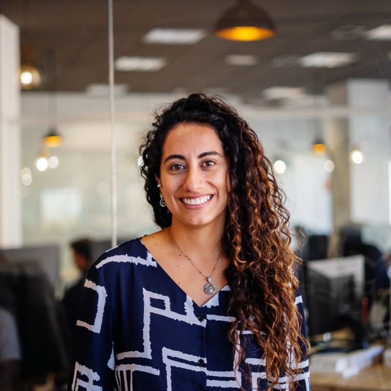 Donna sorridente con capelli castani ricci in un ambiente d'ufficio