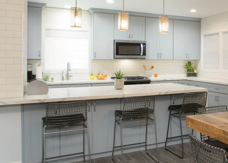 Close up of a rustic farmhouse kitchen bartop seating area. Blue cabinets and quartz countertops. Photo by Chris Darnall.