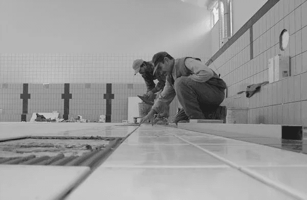 Plumbers working on a tile installation.