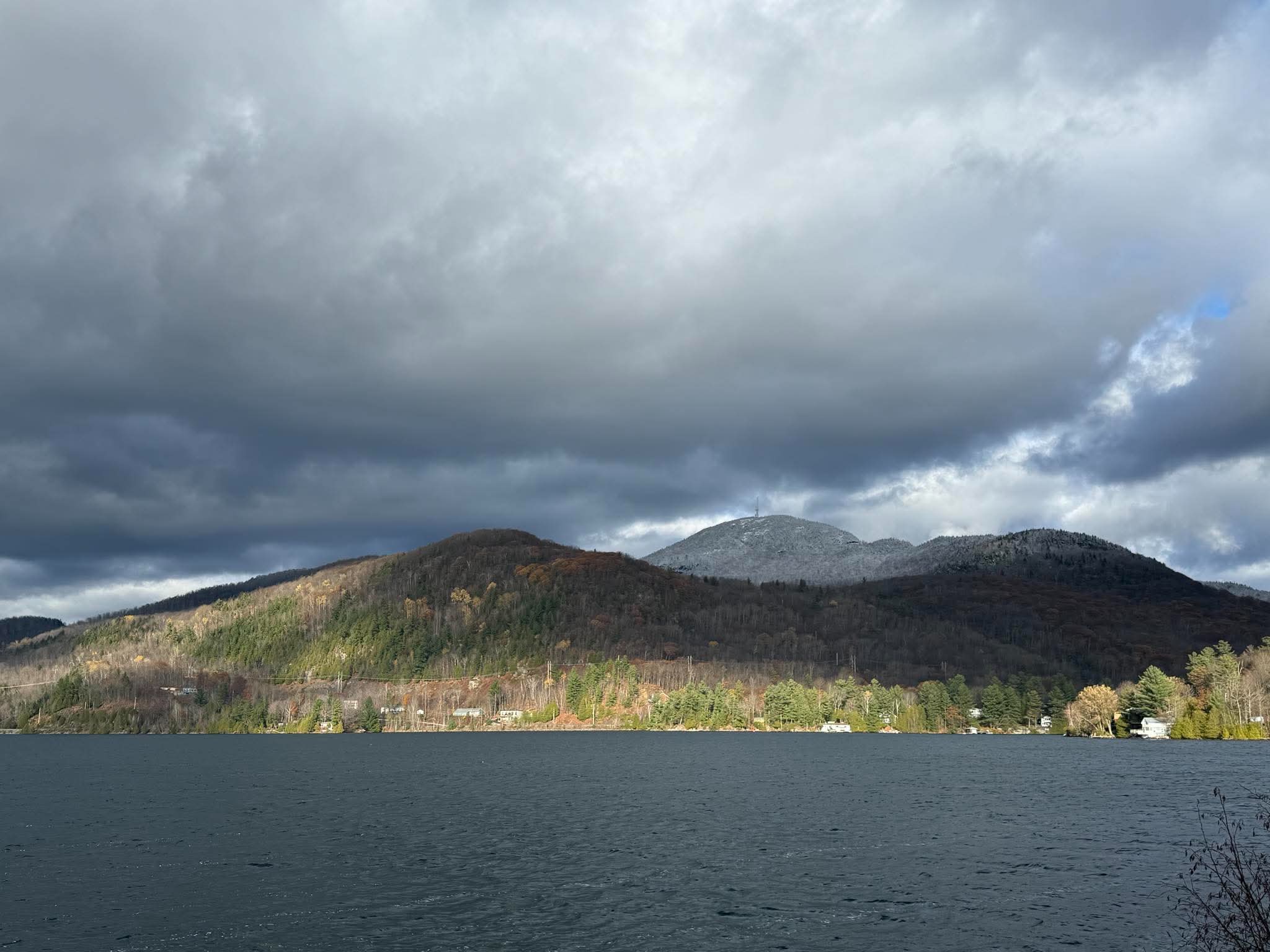 Vue panoramique du lac Orford entouré de collines boisées sous un ciel bleu clair, à Austin en Estrie, Québec.