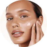 A person gently touches their cheek, highlighting smooth, glowing skin. The close-up conveys a sense of softness and skincare focus.