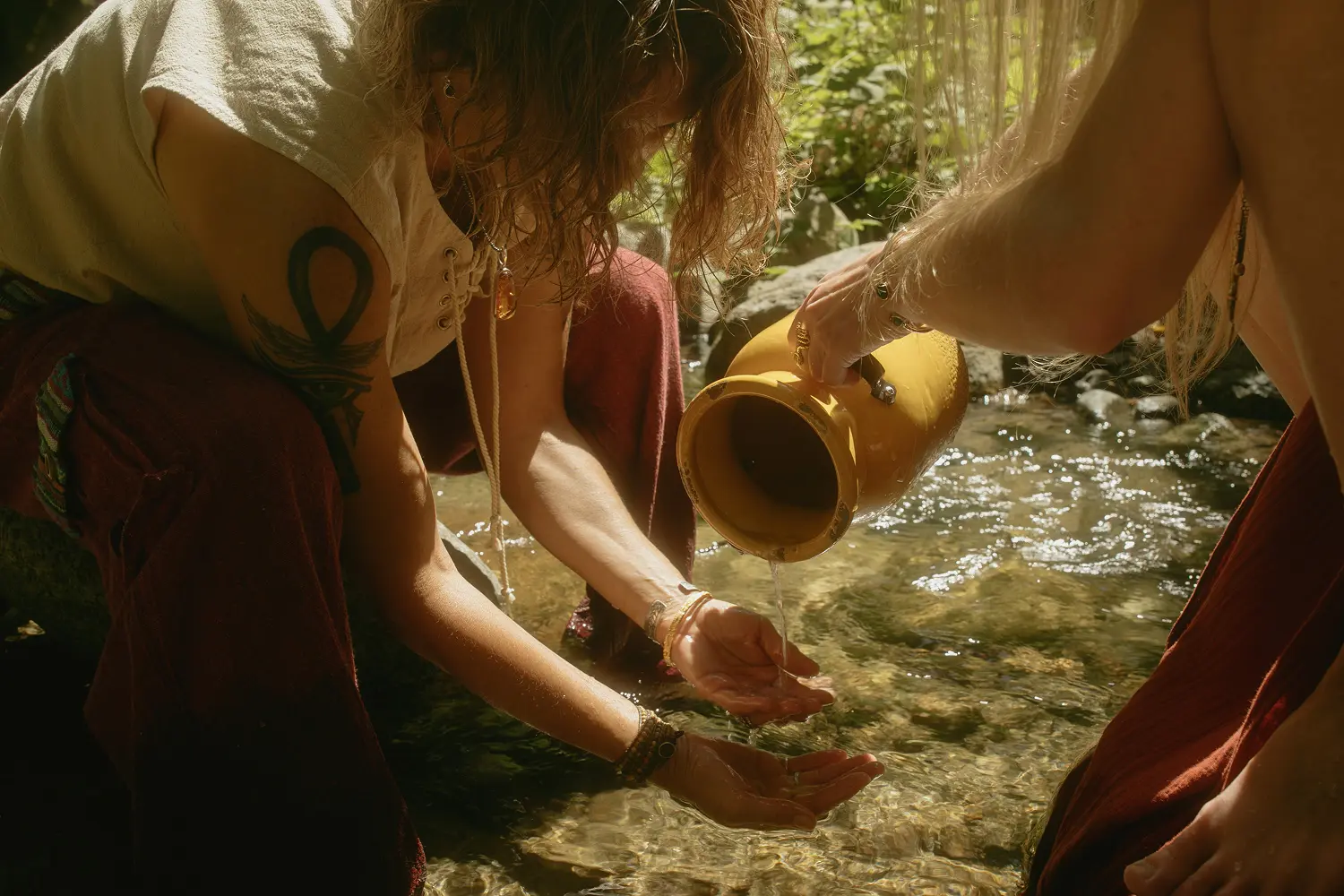 Ceremony participants pouring water offering in jungle stream