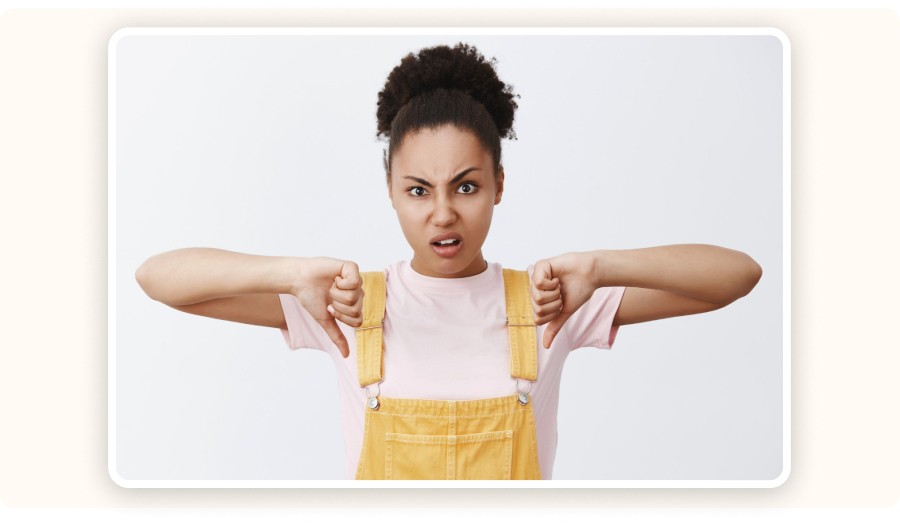 Femme faisant un geste de pouce vers le bas avec expression désapprobatrice.
