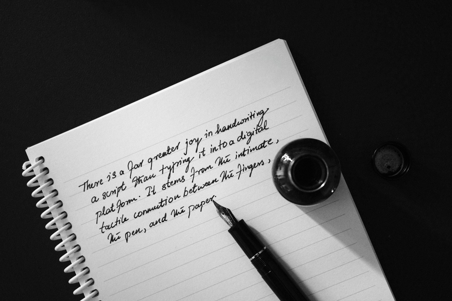Handwritten notebook page beside a fountain pen and ink bottle