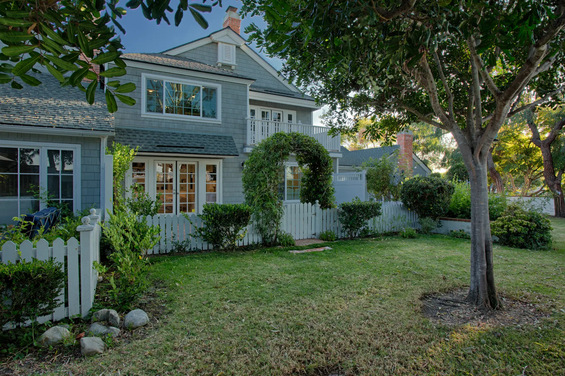 Quaint Cape Cod style home with white picket fence and lush landscaping from the Dana Point Cape Cod remodel. Photo by Chris Darnall.