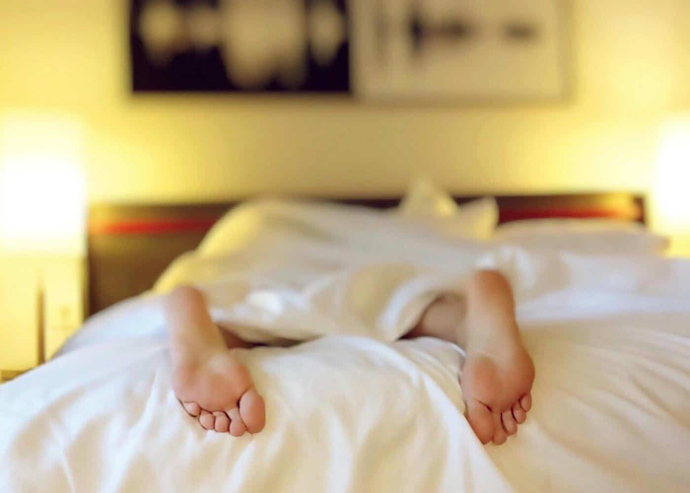 Feet sticking out of bed covers showcasing an exhausted person
