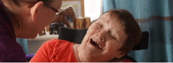 Caregiver interacting with disabled person at home.