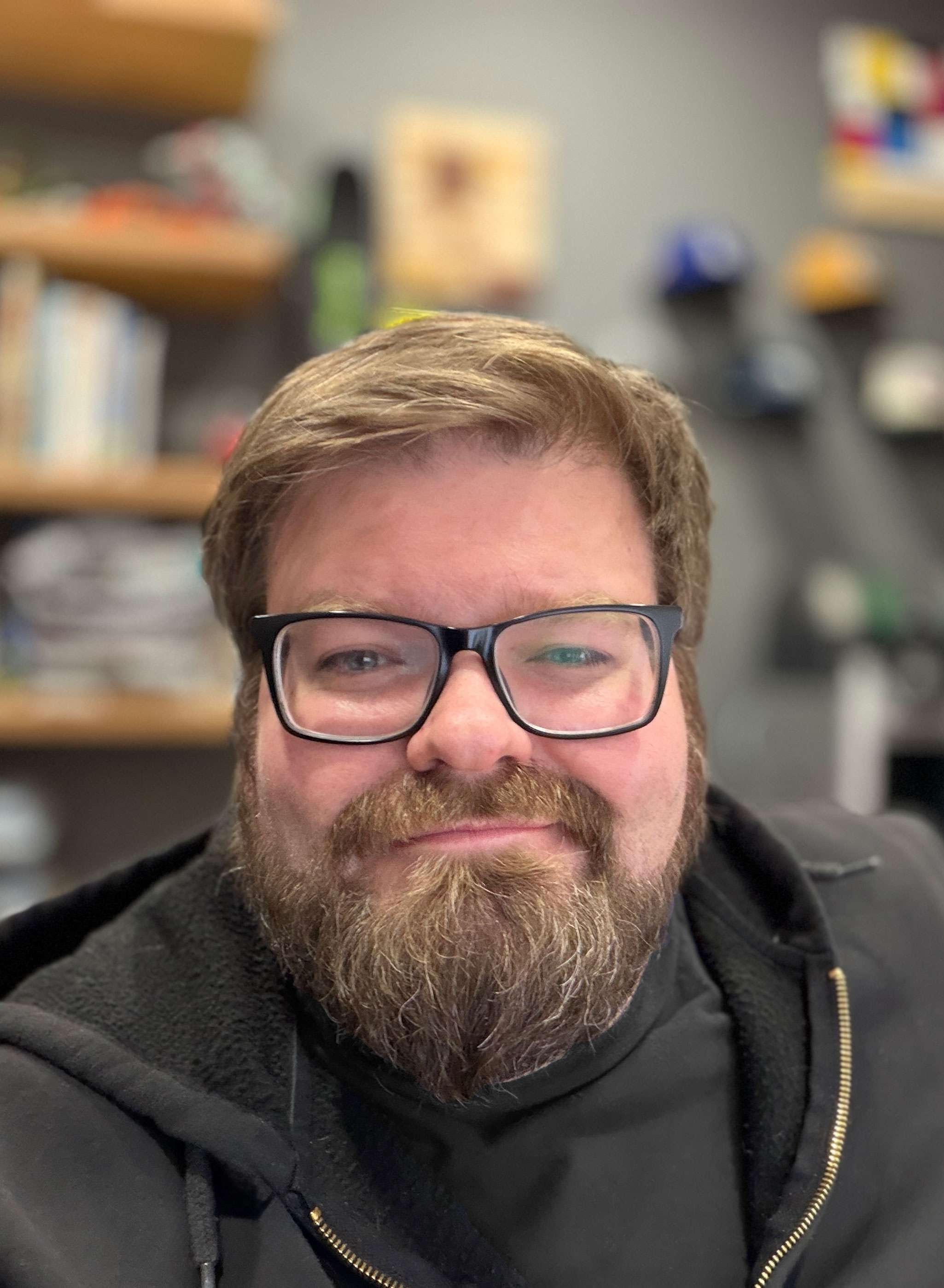 Portrait of Brian Talbot- He has black framed glasses and a short beard.