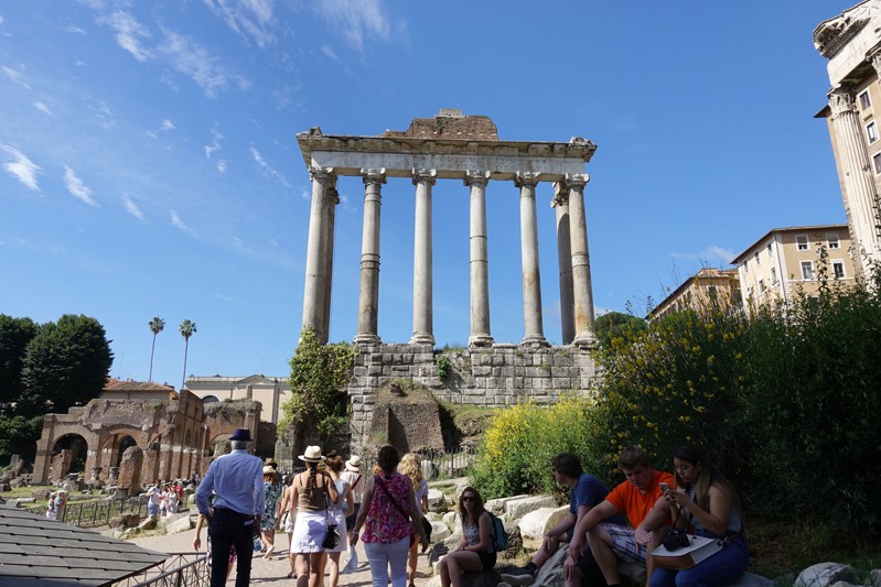 A photo of a group of people visiting some old roman temple remains.